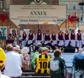 A women's choir dressed in traditional garb performs on stage at the market place at Rynek Glowny, the main square in Krakow, Poland.